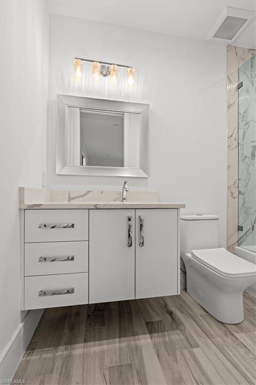 Bathroom featuring vanity, a marble finish shower, and light wood-type flooring