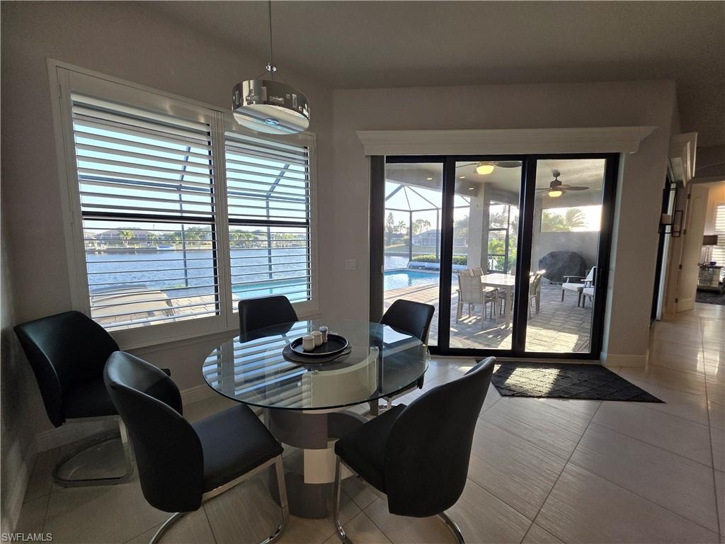 Dining room featuring a water view, tile patterned flooring, and a sunroom