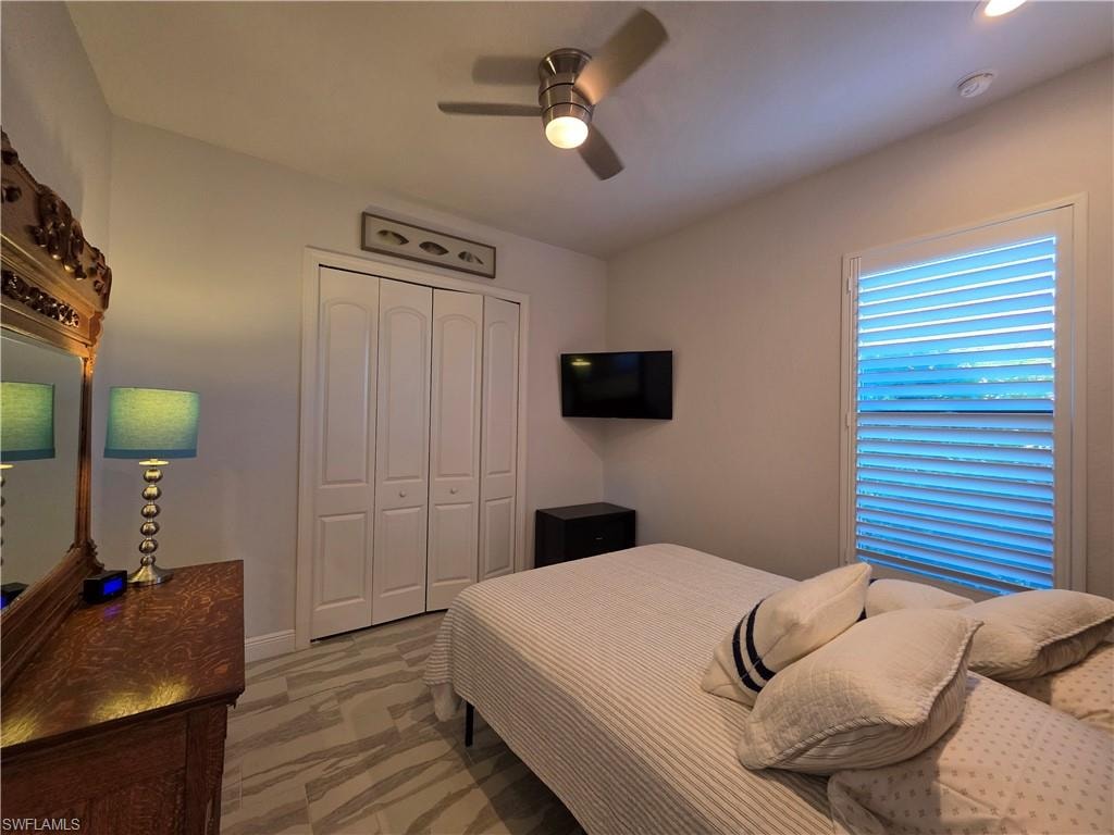 Bedroom with a closet, light marble finish floors, and ceiling fan