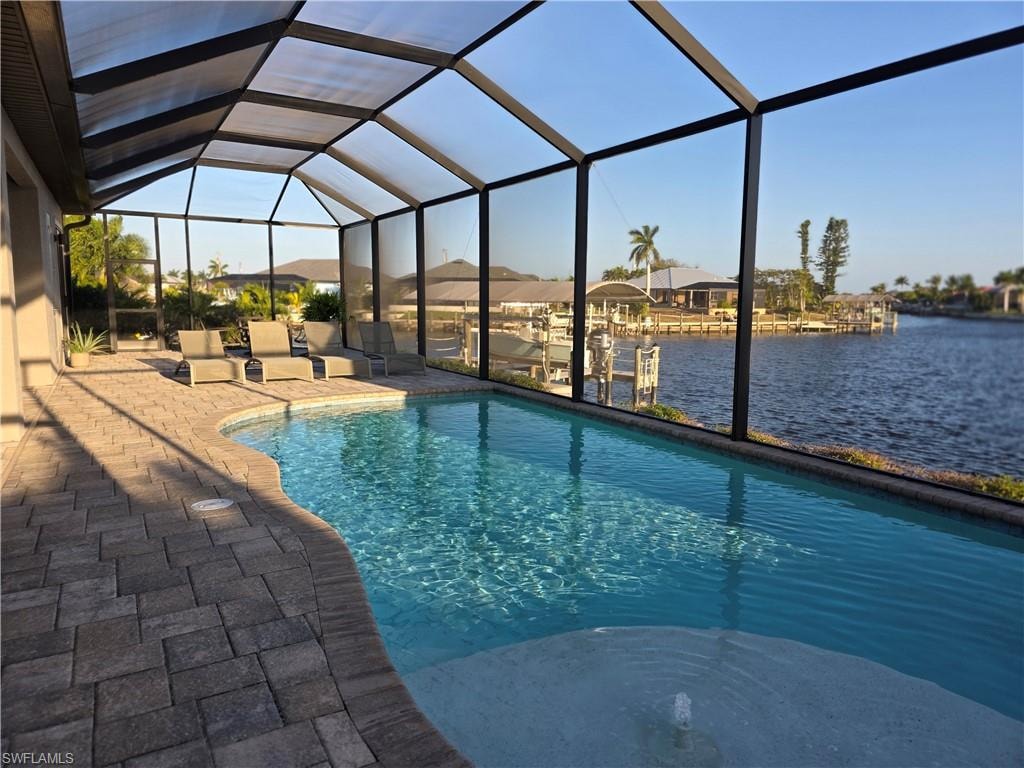 Outdoor pool with a sunroom, glass enclosure, a water view, and a patio area