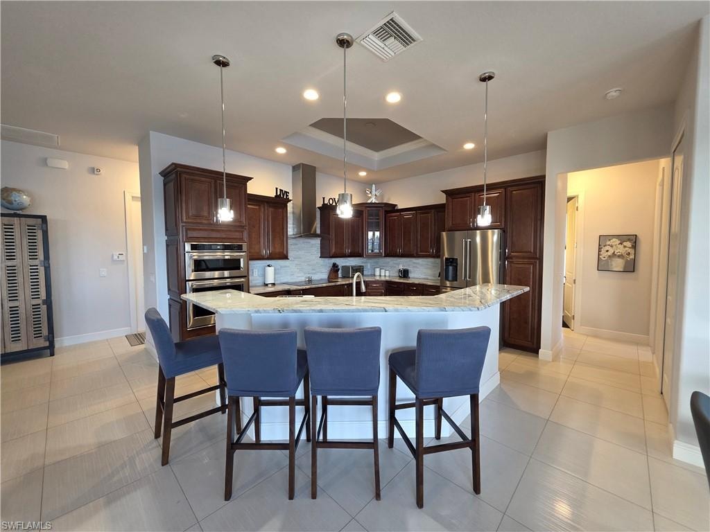 Kitchen featuring decorative light fixtures, backsplash, a kitchen bar, dark brown cabinetry, and recessed lighting