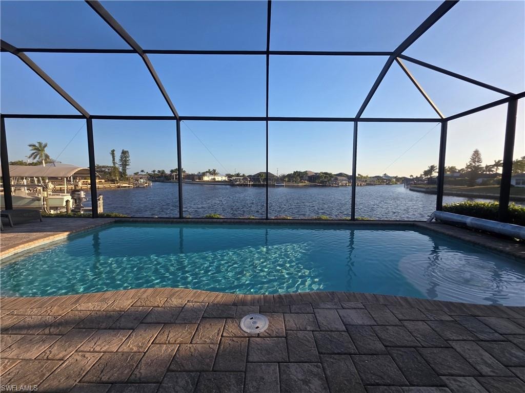 Swimming pool featuring a sunroom, a water view, and glass enclosure