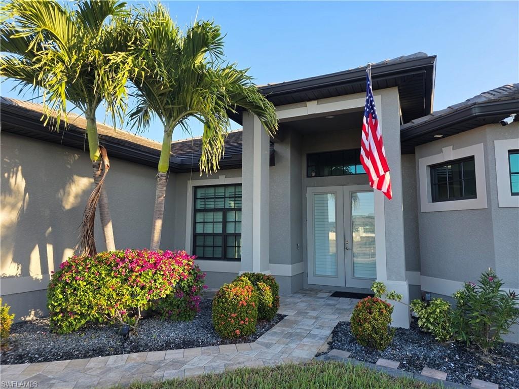 View of exterior entry with stucco siding and french doors