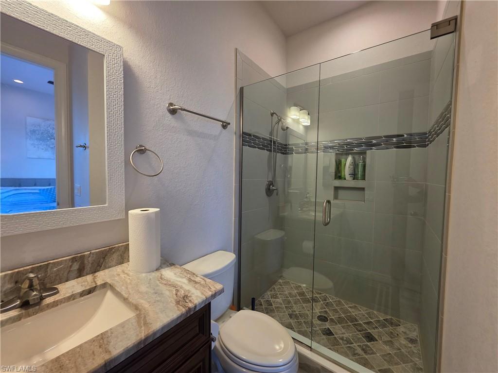 Full bathroom / Pool Bath featuring a textured wall, vanity, and a stall shower