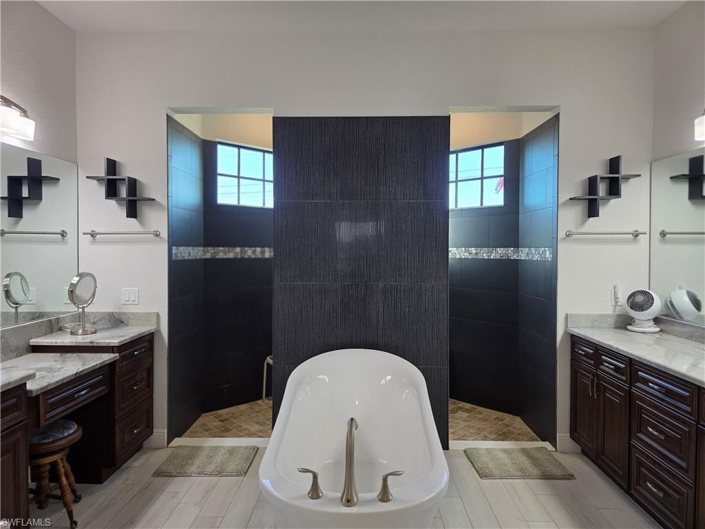 Bathroom with walk in shower, vanity, a freestanding tub, and healthy amount of natural light