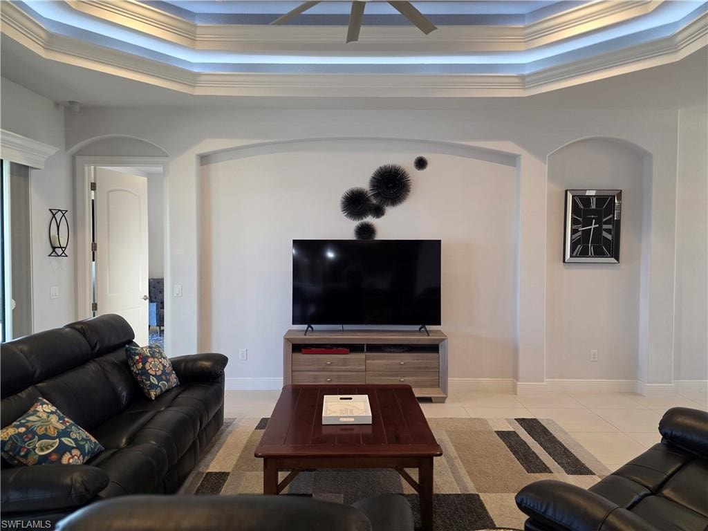 Tiled living room featuring crown molding and a raised ceiling