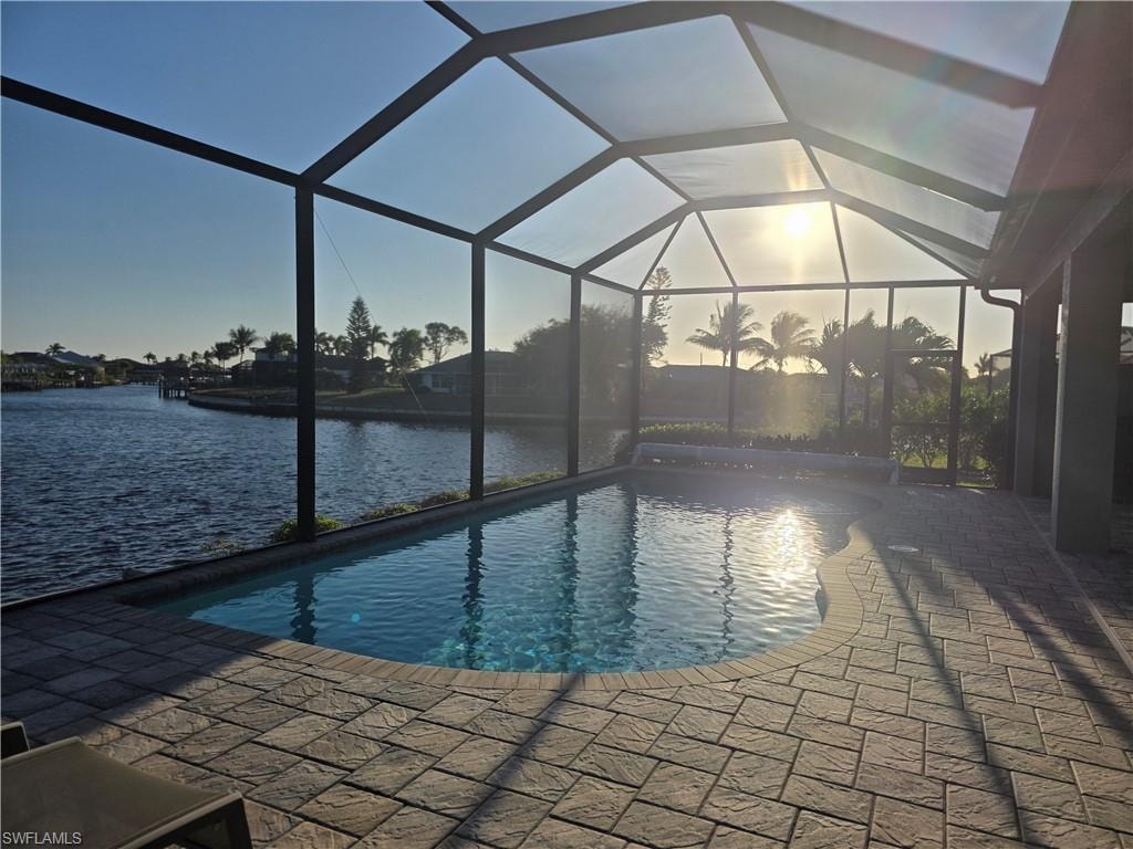 Pool at dusk featuring glass enclosure, an outdoor pool, and a sunroom
