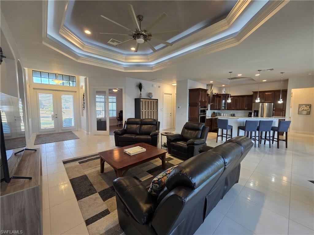 Living area featuring crown molding, recessed lighting, a ceiling fan, light tile patterned floors, and a tray ceiling