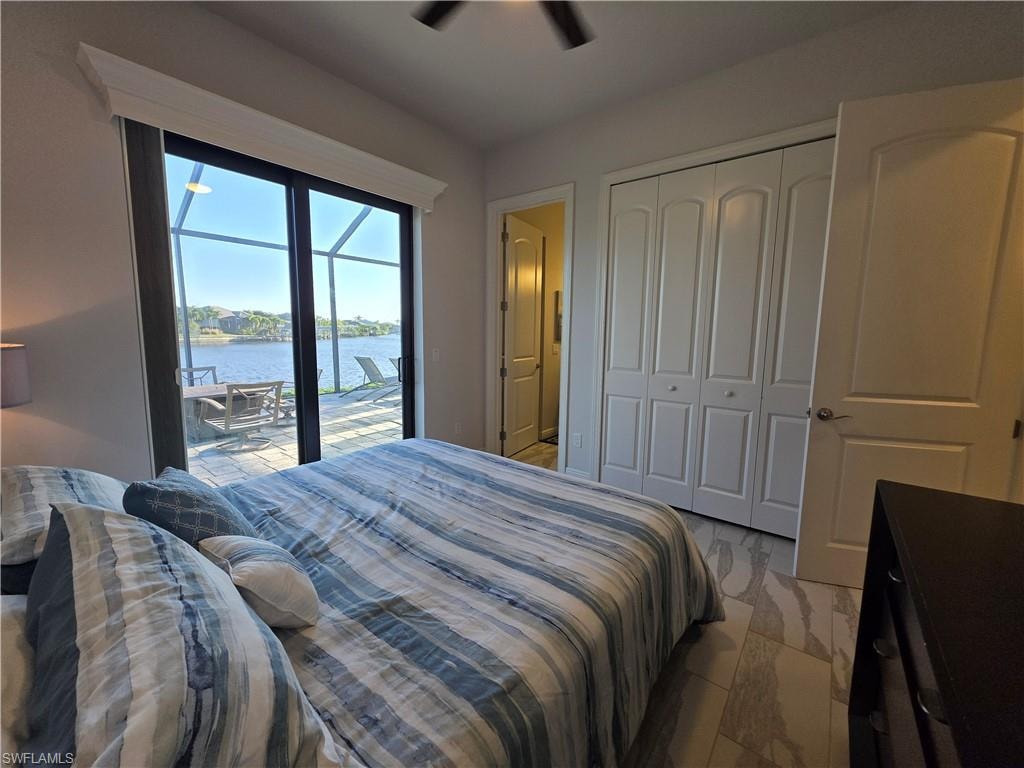 Bedroom featuring a water view, access to exterior, ceiling fan, and a closet