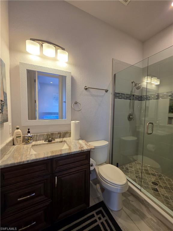 Bathroom / Pool Bath with a stall shower, vanity, and a textured wall