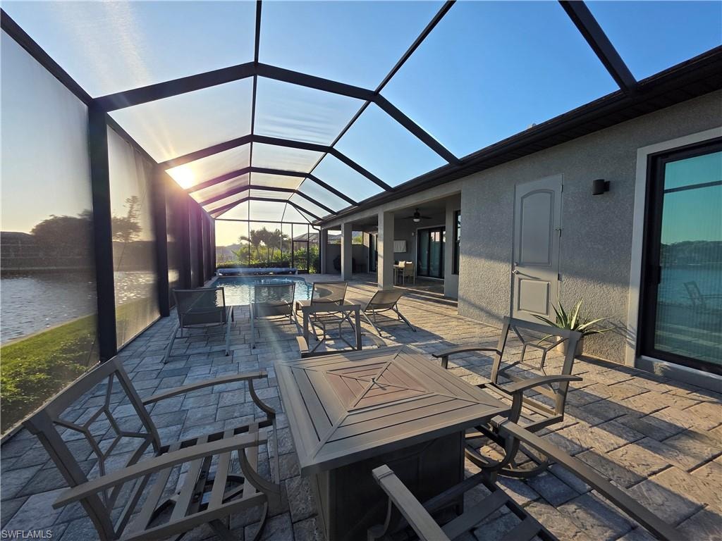 View of patio featuring a sunroom, glass enclosure, a pool with connected hot tub, and a ceiling fan