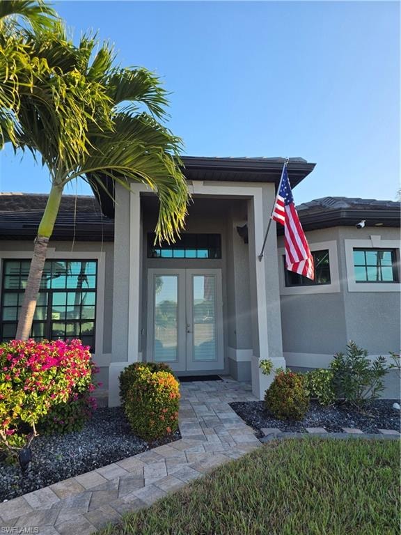 View of exterior entry with stucco siding and french doors