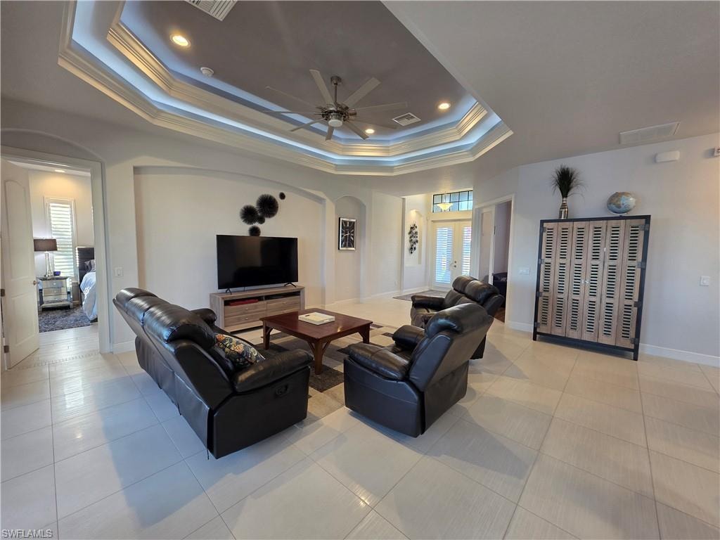 Living room with arched walkways, crown molding, recessed lighting, light tile patterned floors, and a ceiling fan