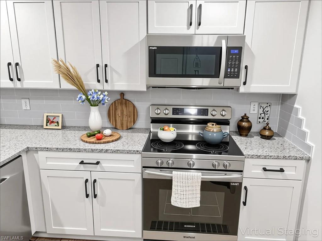 Kitchen with appliances with stainless steel finishes, white cabinetry, tasteful backsplash, and light stone counters