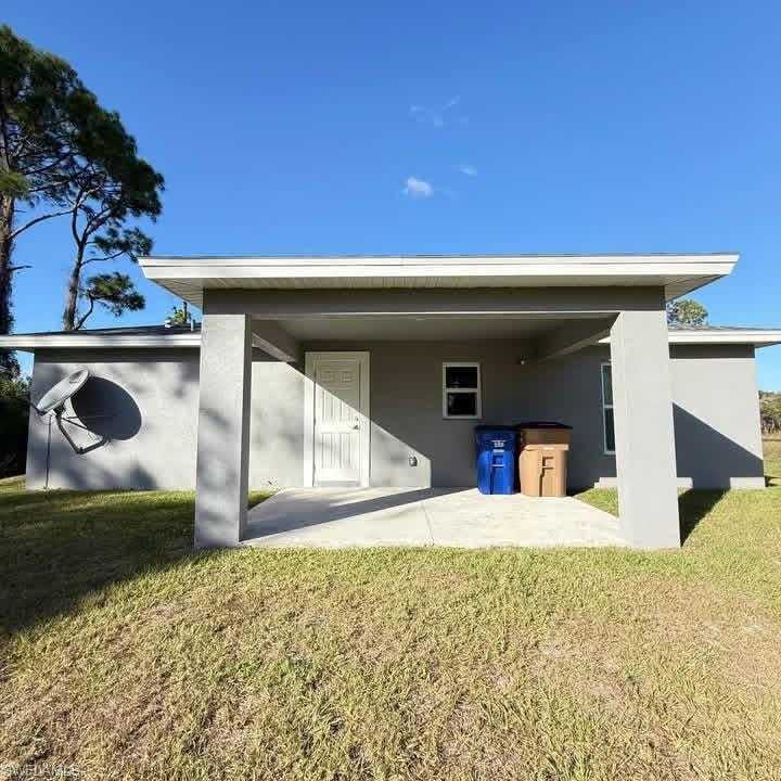 Back of property featuring a lawn and a patio
