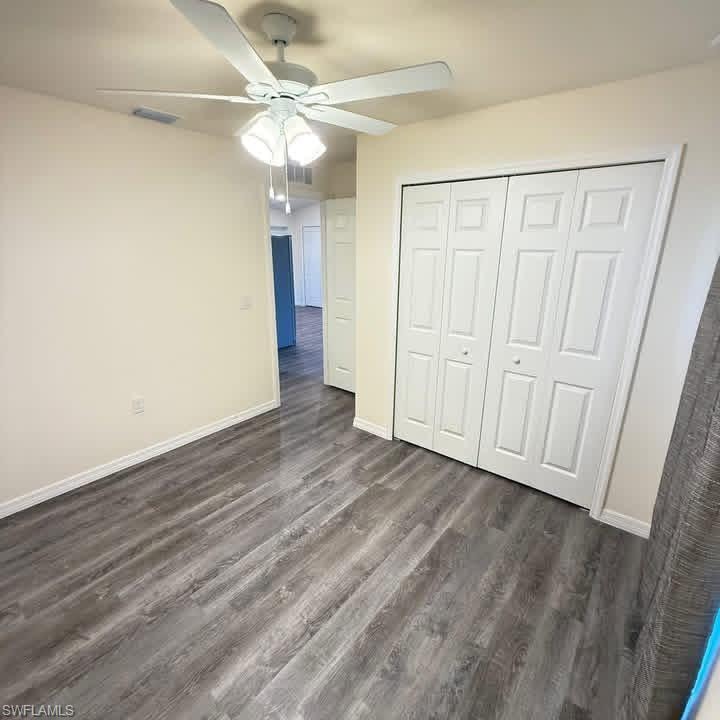 Unfurnished bedroom with dark wood-type flooring, ceiling fan, and a closet