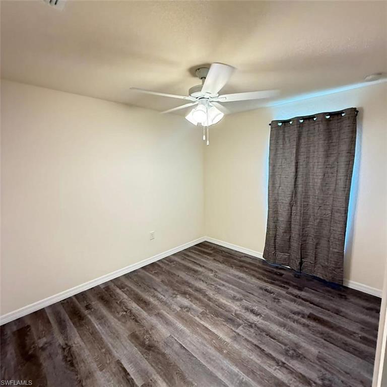 Spare room featuring dark wood-style flooring and ceiling fan