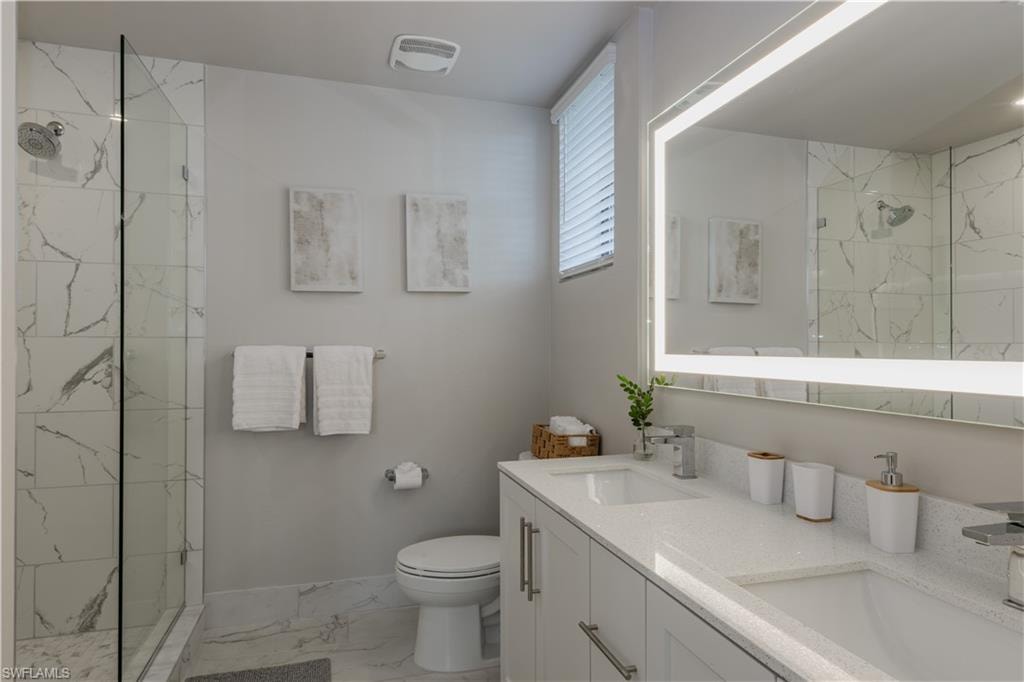 Full bath featuring light marble finish flooring, double vanity, and a marble finish shower