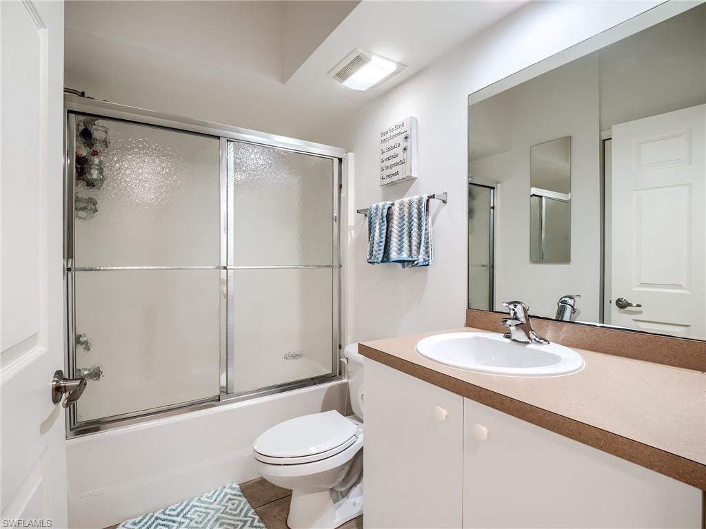 Bathroom with vanity, enclosed tub / shower combo, and light tile patterned floors