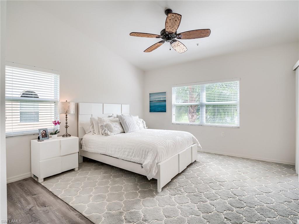 Bedroom featuring ceiling fan, lofted ceiling, and multiple windows