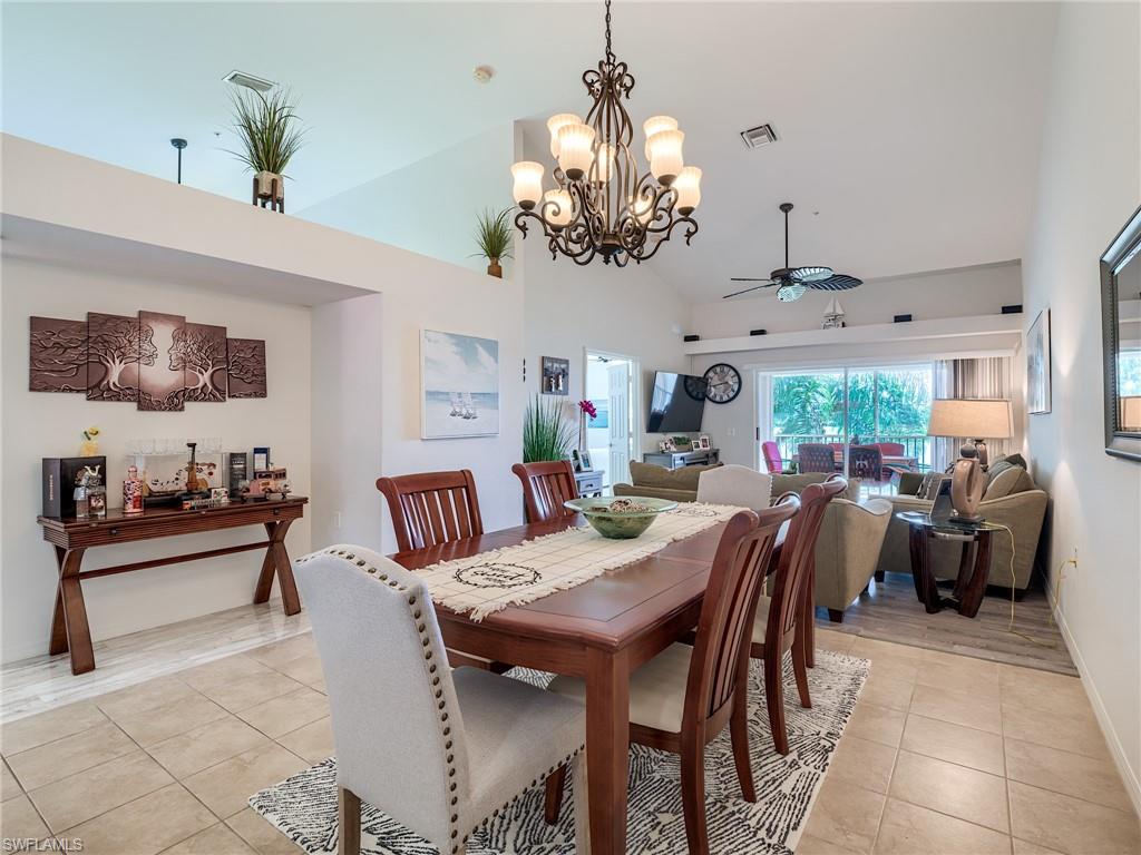 Dining room with a ceiling fan, light tile patterned flooring, high vaulted ceiling, and a chandelier