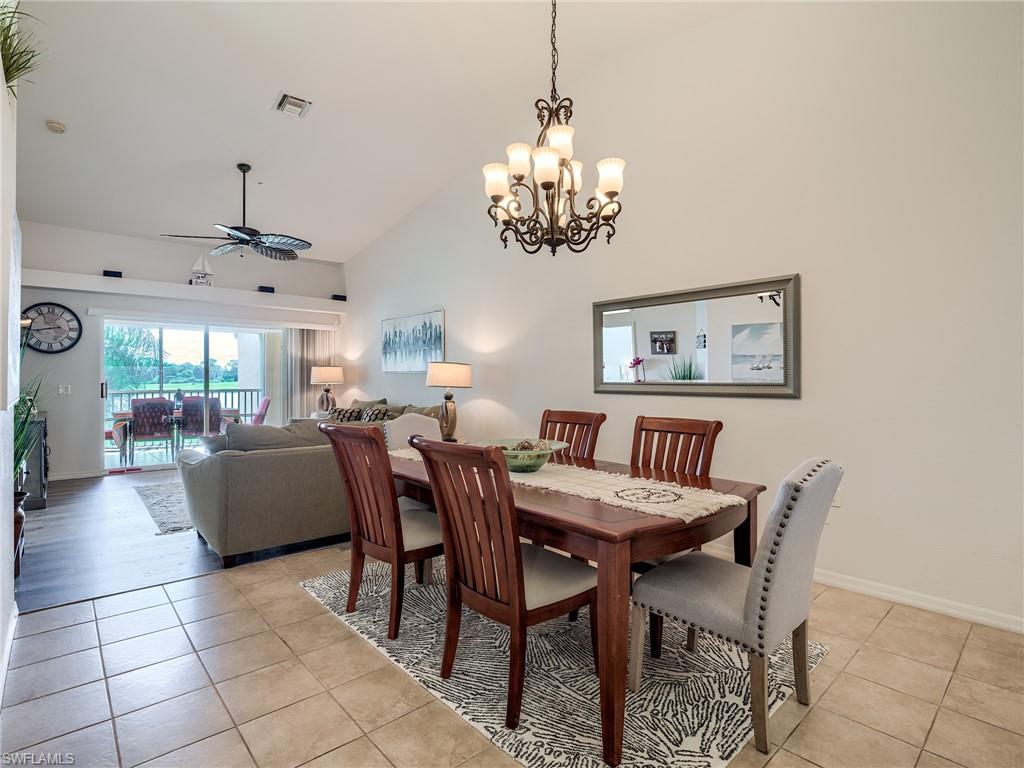 Dining area with a ceiling fan, light tile patterned floors, a chandelier, and high vaulted ceiling