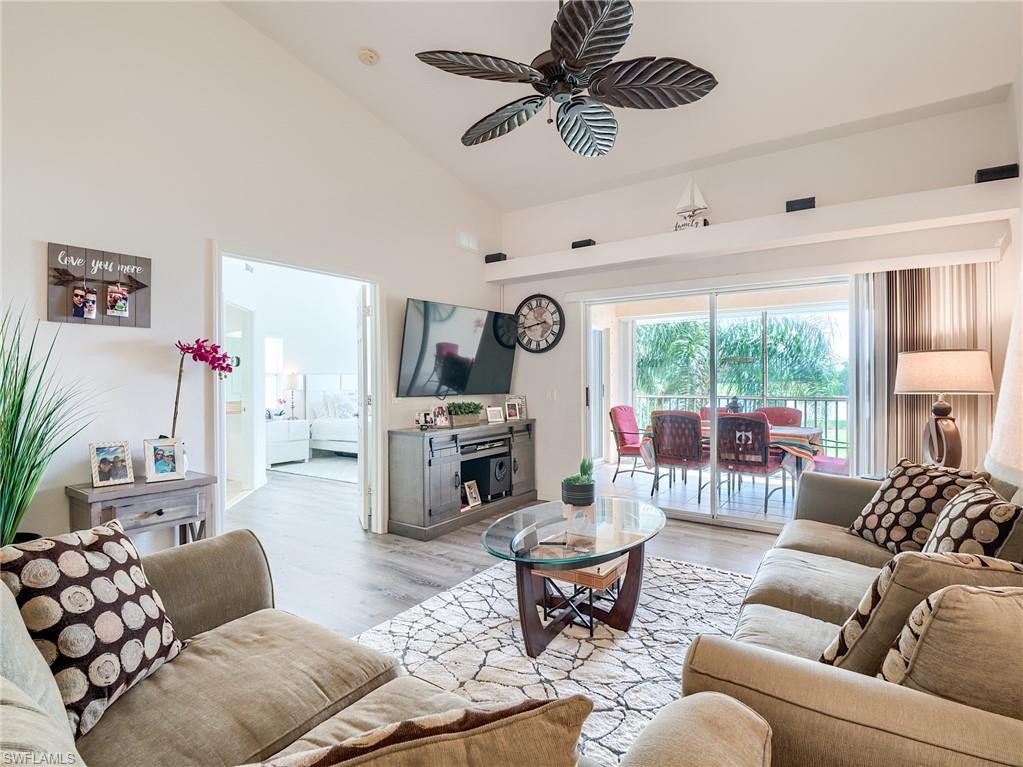 Living room with wood finished floors, high vaulted ceiling, and a ceiling fan