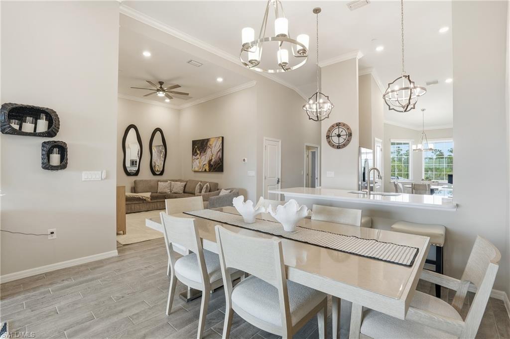 Dining room with ceiling fan, wood finish floors, ornamental molding, recessed lighting, and a chandelier
