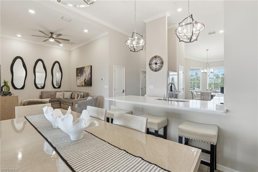Dining area featuring crown molding, recessed lighting, a ceiling fan, a towering ceiling, and a chandelier