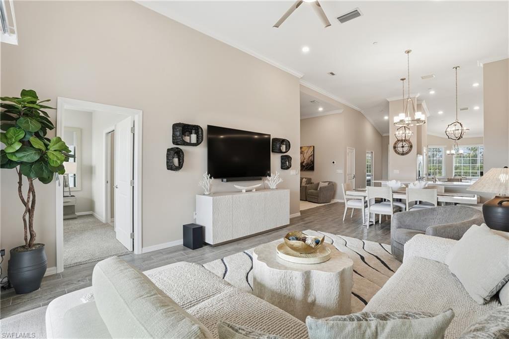 Living area featuring wood finish floors, crown molding, recessed lighting, and a chandelier