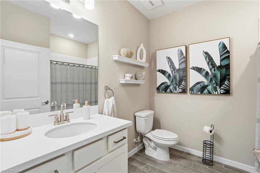 Full bath with vanity, a shower with shower curtain, and wood finish floors