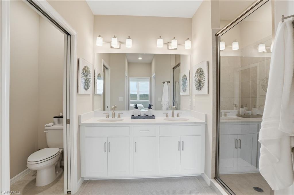 Bathroom featuring a shower stall, double vanity, and light tile patterned floors