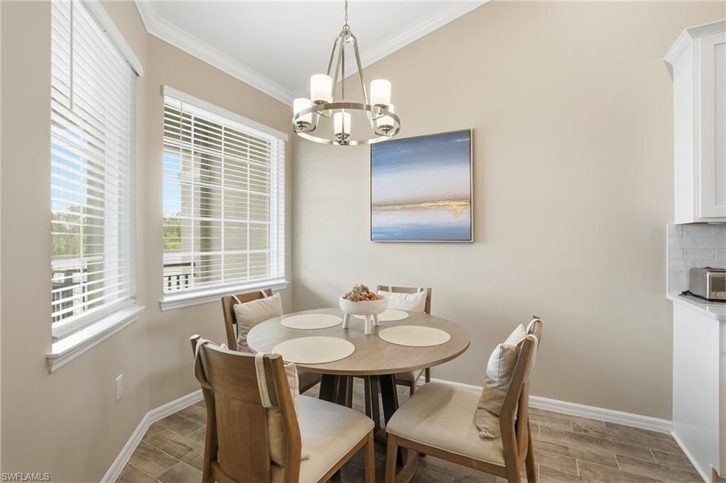 Dining area featuring ornamental molding, plenty of natural light, wood tiled floors, and a chandelier