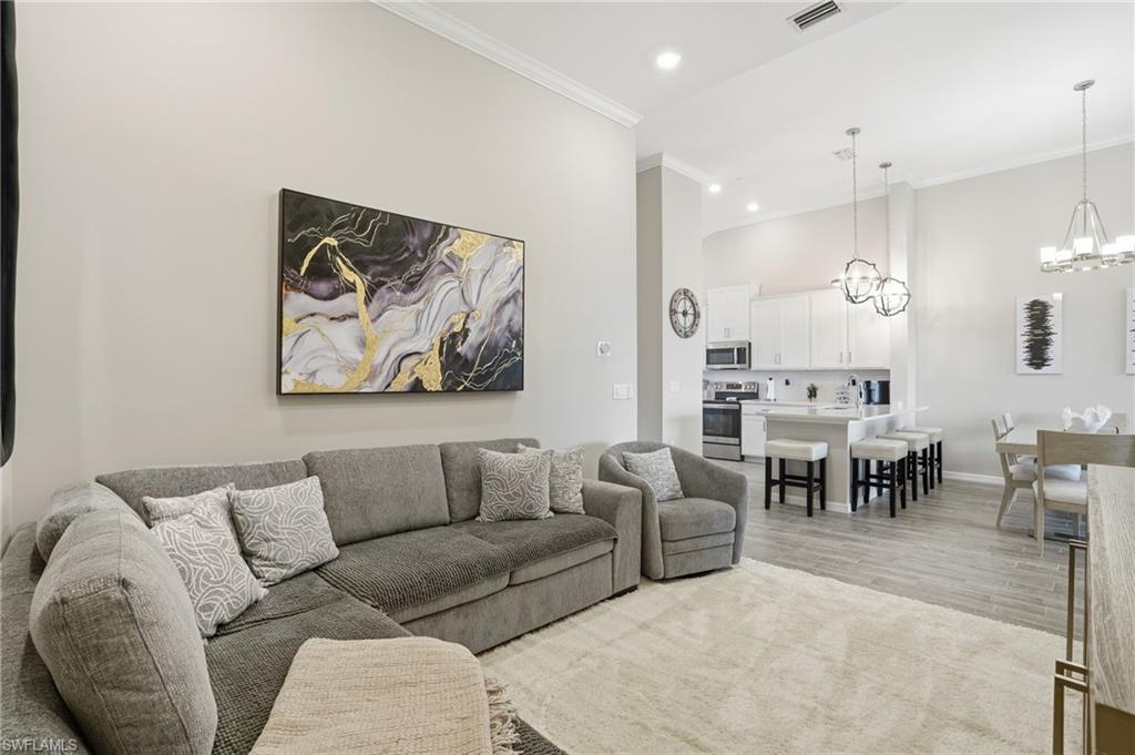 Living area with a chandelier, ornamental molding, recessed lighting, and light wood-type flooring