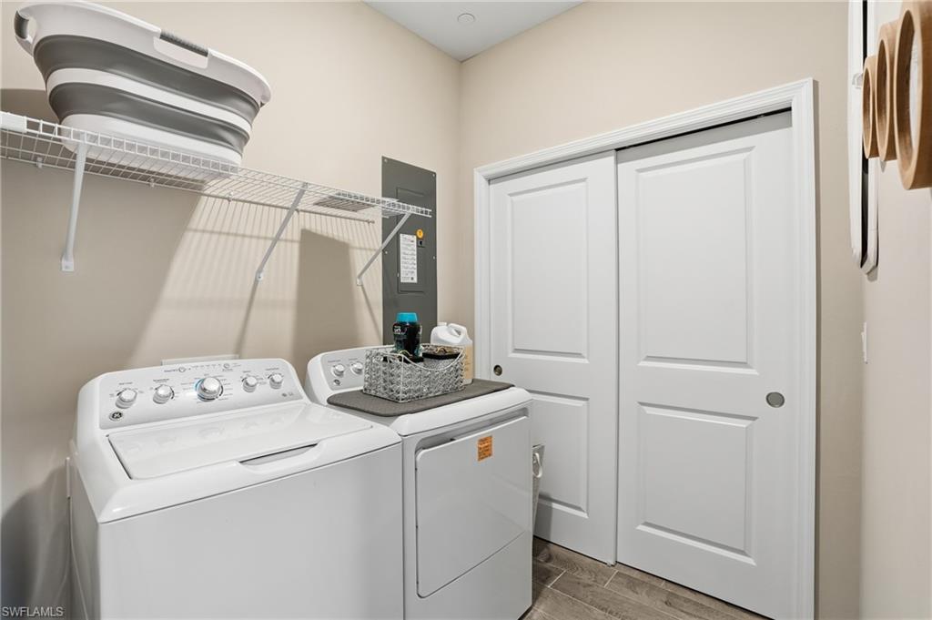 Laundry area featuring electric panel, wood finish floors, and washing machine and dryer