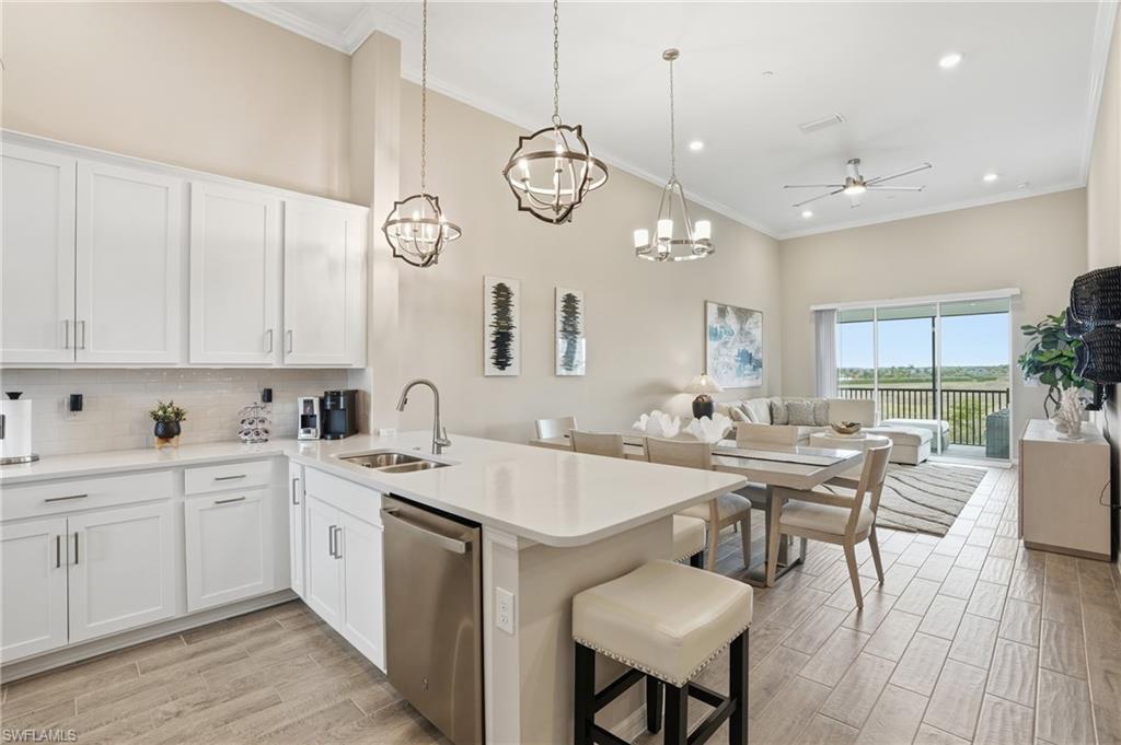 Kitchen with white cabinets, dishwasher, open floor plan, decorative light fixtures, and wood tiled floors