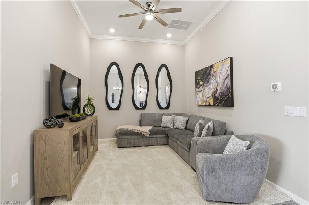 Living room with ornamental molding, a ceiling fan, and carpet