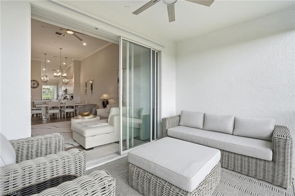 Living area with a ceiling fan, a textured wall, a chandelier, and ornamental molding