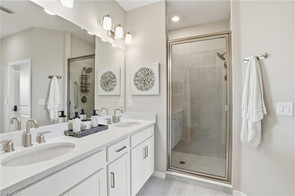 Full bathroom with double vanity, a shower stall, and light tile patterned floors
