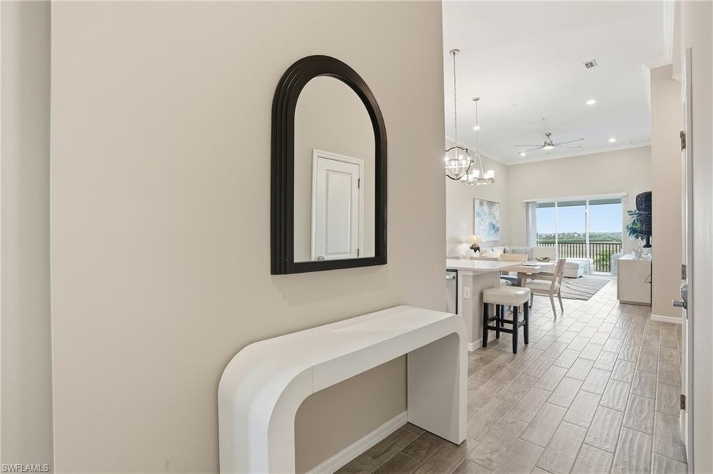 Hall featuring wood finish floors, ornamental molding, recessed lighting, and a chandelier