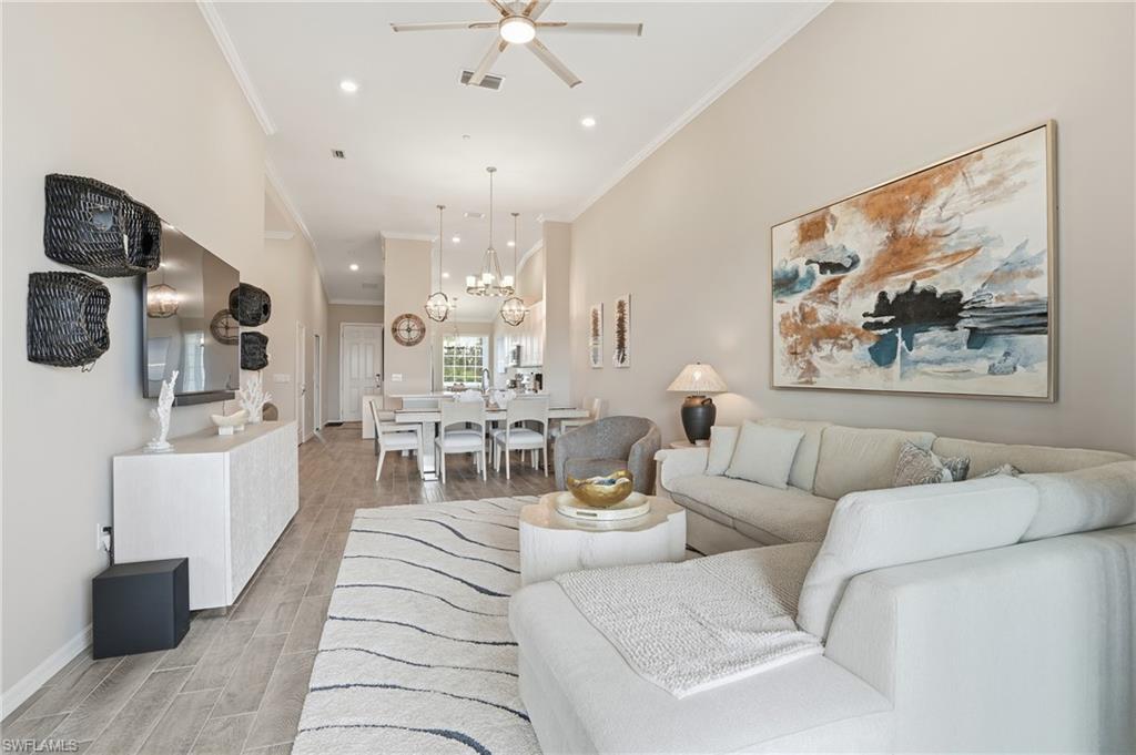Living area featuring wood tiled floors, ornamental molding, recessed lighting, a chandelier, and a ceiling fan
