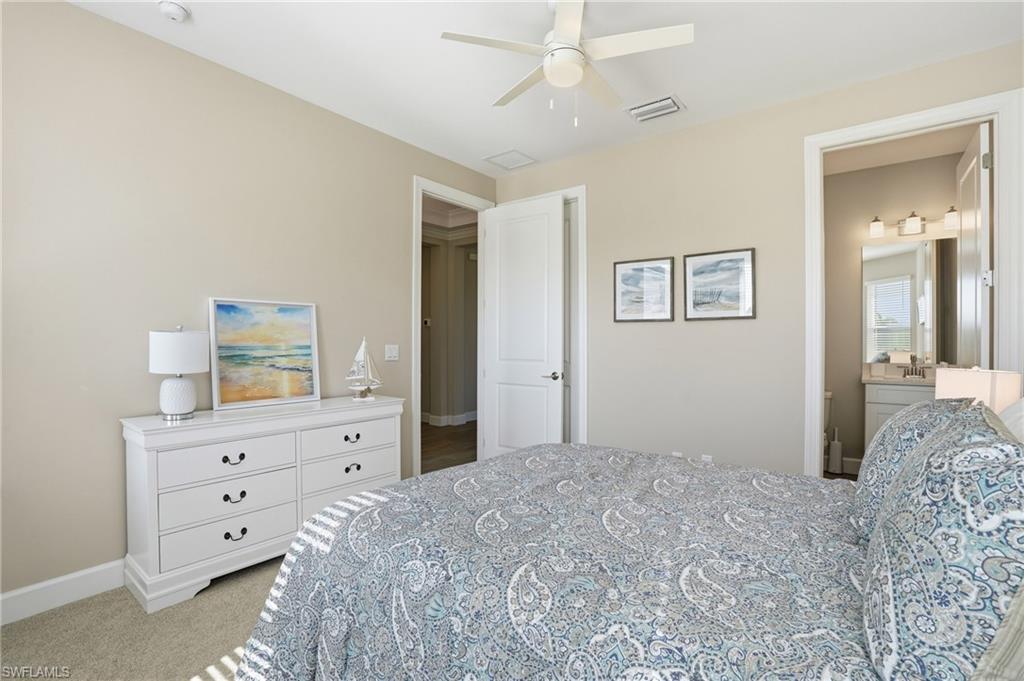 Bedroom with light colored carpet, ceiling fan, and ensuite bathroom