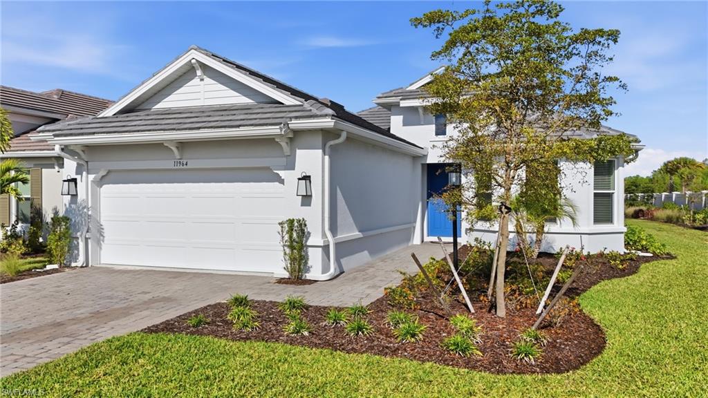 View of front of home with a garage, decorative driveway, stucco siding, and a front lawn