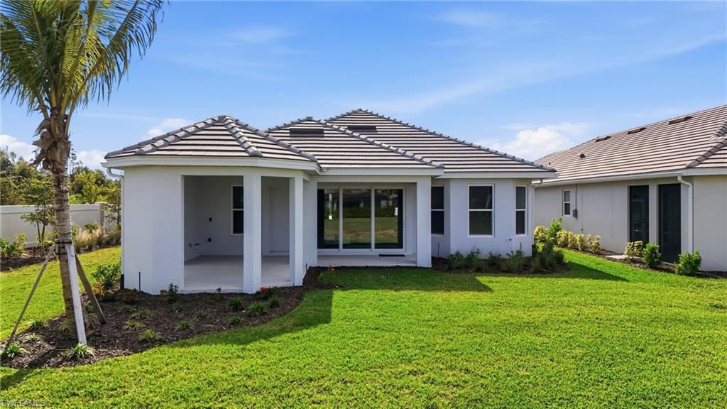 Back of property featuring a patio area, stucco siding, a yard, and a tile roof