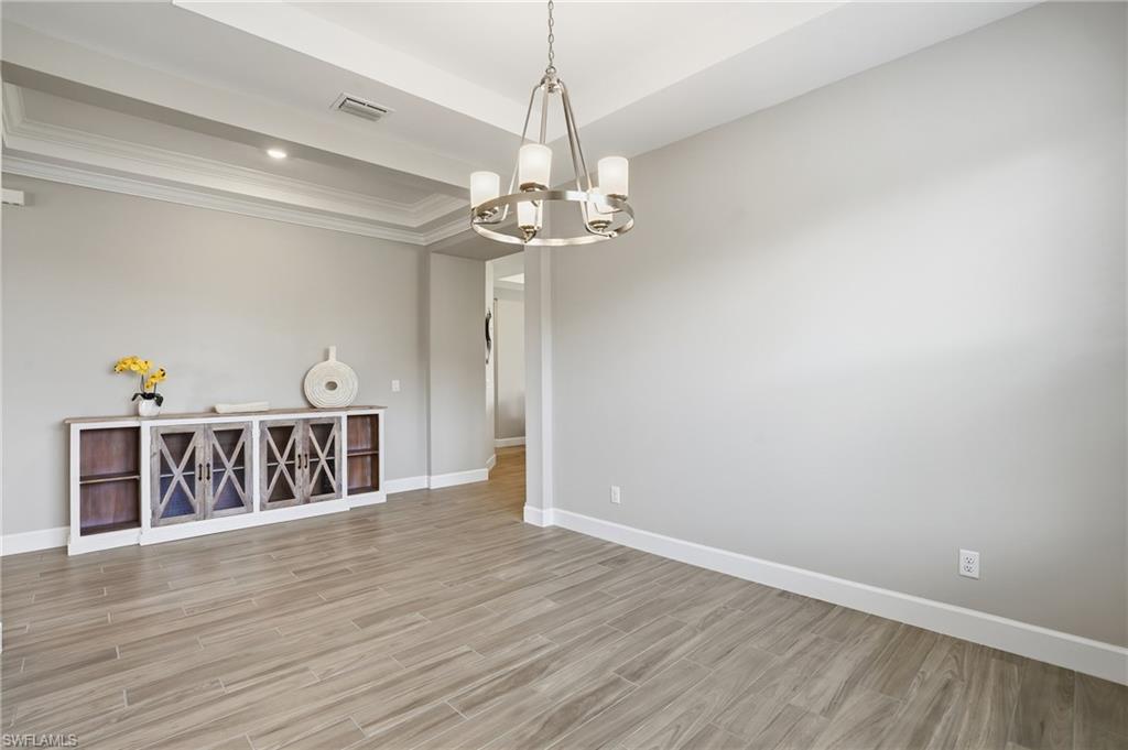 Unfurnished room featuring wood finish floors, a chandelier, and a tray ceiling