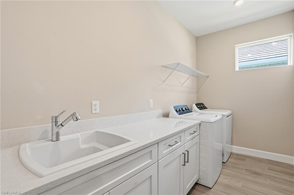 Laundry room with wood tiled floors, independent washer and dryer, and cabinet space