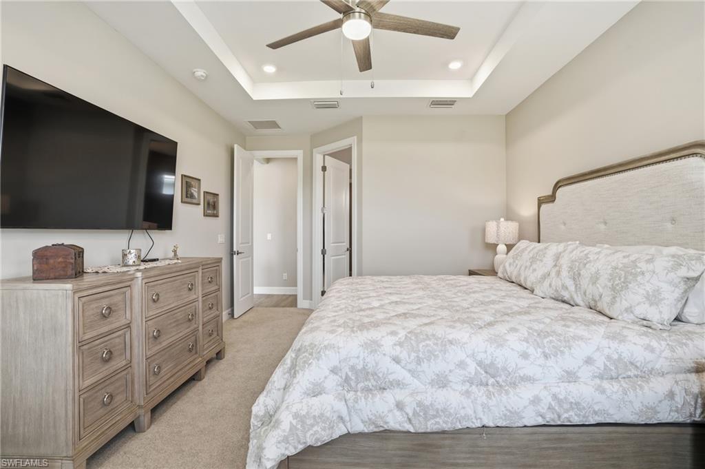 Bedroom with a raised ceiling, a ceiling fan, light carpet, and recessed lighting
