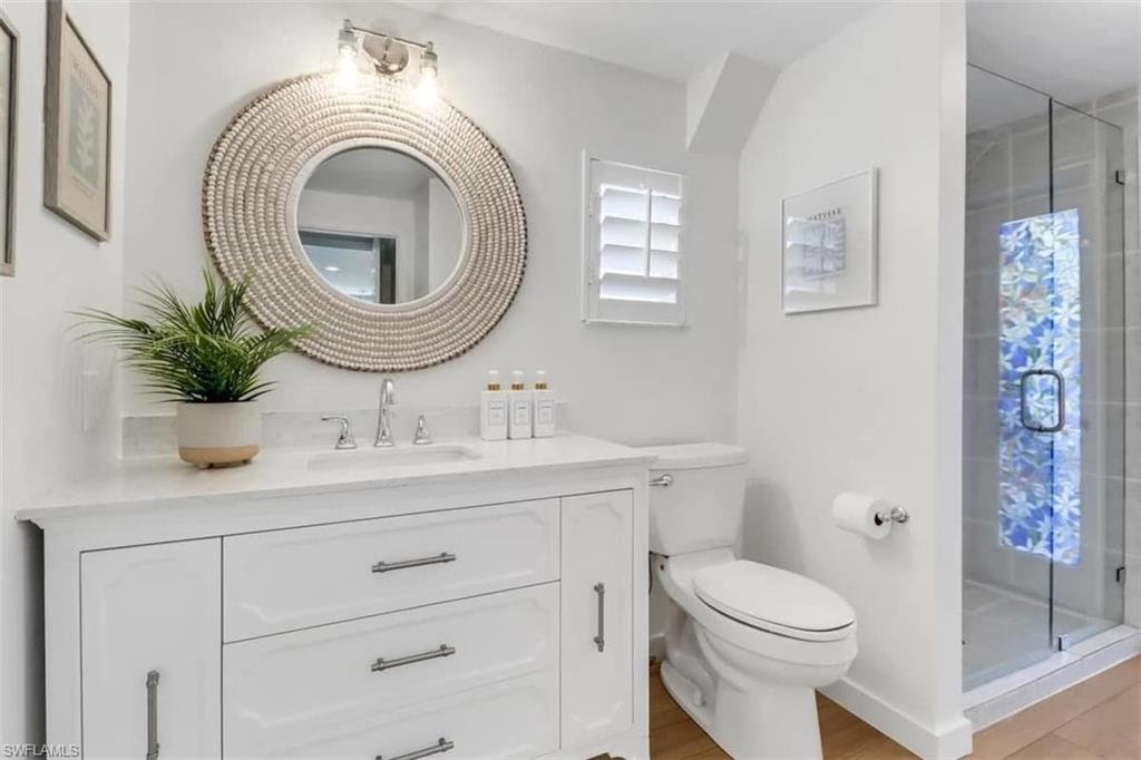 Bathroom featuring hardwood / wood-style flooring, vanity, toilet, and a shower with door