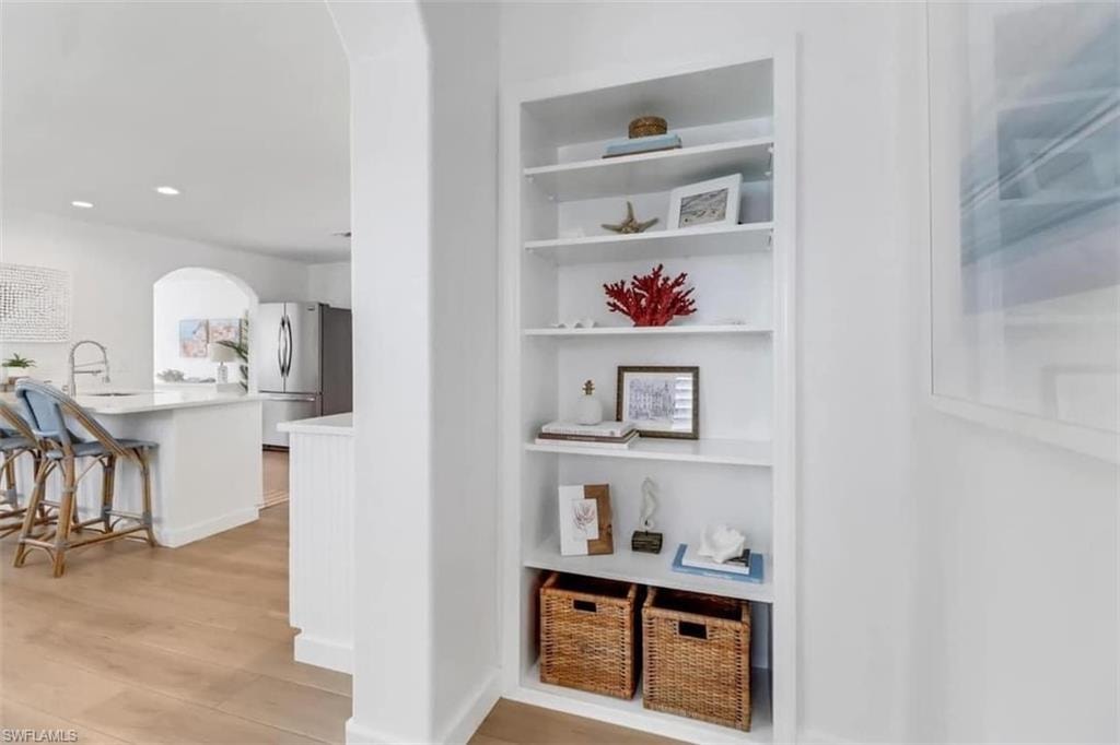 Corridor with built in shelves, light hardwood / wood-style flooring, and sink