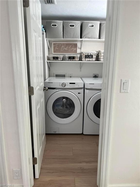 Washroom with separate washer and dryer and light wood-type flooring